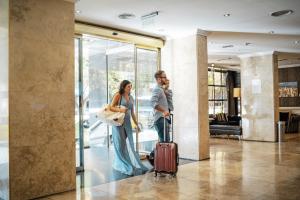 a man and a woman with a suitcase in a lobby at Amérian Córdoba Park Hotel in Córdoba