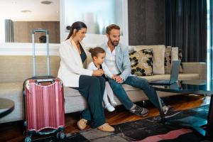 a family sitting on a couch with a suitcase at Amérian Córdoba Park Hotel in Córdoba