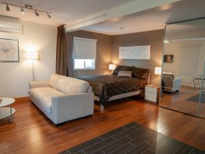 1 dormitorio con 1 cama y 1 sofá blanco en Résidence Touristique Chicoutimi, en Saguenay