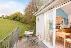 a balcony of a house with a table and a kitchen at Seaside Retreat with Stunning Sea Views in Talland