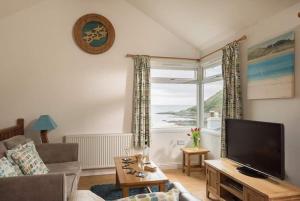 un soggiorno con TV e una grande finestra di Seaside Retreat with Stunning Sea Views a Talland
