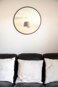 a mirror on a wall above a couch with pillows at Wykebeck Mount by Our Home Short Stays in Killingbeck