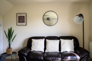 a leather couch in a living room with a mirror at Wykebeck Mount by Our Home Short Stays in Killingbeck