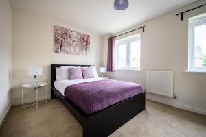 a bedroom with a bed with a purple blanket and two windows at Wykebeck Mount by Our Home Short Stays in Killingbeck