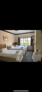 a bedroom with three beds and a large window at The Cranley Hotel in Cranleigh