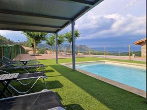 a swimming pool with chairs and a table at Mas el Coll in El Gurb
