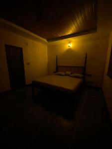 a bedroom with a bed in a dark room at Ooru homestay in Udupi