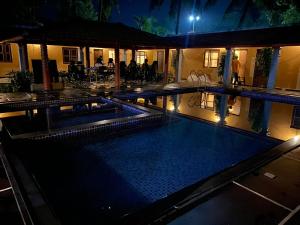 a swimming pool at night with people sitting at a restaurant at Ooru homestay in Udupi