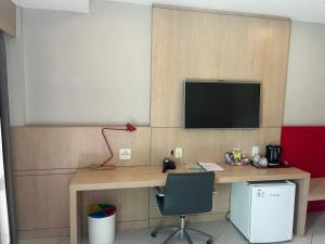 Flat Barra da tijuca في ريو دي جانيرو: غرفة بها مكتب مع تلفزيون على الحائط