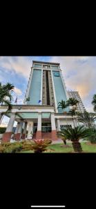 een hoog gebouw met palmbomen ervoor bij Flat Barra da tijuca in Rio de Janeiro