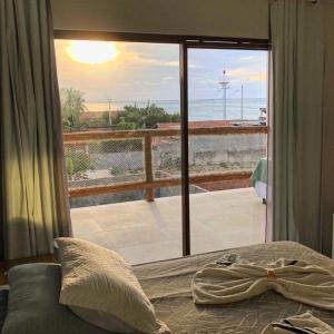 a bedroom with a window with a view of the ocean at Pousada farol in Areia Branca