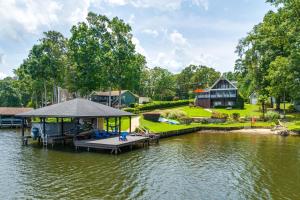 un muelle en un lago con una casa en Luxe Lake Sinclair Living Private Dock and Beach! en Resseaus Crossroads