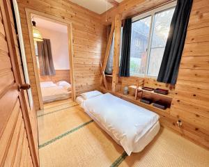 um quarto com uma cama num chalé de madeira em Moment Chalet Hakuba em Hakuba