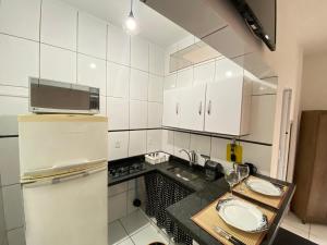 a white kitchen with a refrigerator and a sink at Apto Santos Gonzaga 50mtrs Praia in Santos +7 photos