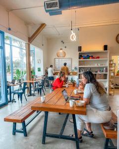 a woman sitting at a table in a restaurant at ITH Santa Barbara Beach Hostel in Santa Barbara