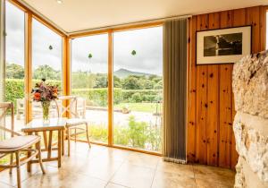 sala de estar con mesa, sillas y ventana grande en Sychpant Barn en Velindre