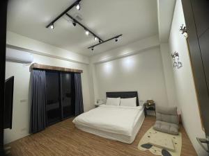 a bedroom with a white bed and a window at 宜蘭包棟民宿 嵐恬苑 歡唱 電動麻將 燒烤 in Yilan City