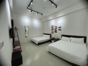 a bedroom with two beds and a television in it at 宜蘭包棟民宿 嵐恬苑 歡唱 電動麻將 燒烤 in Yilan City