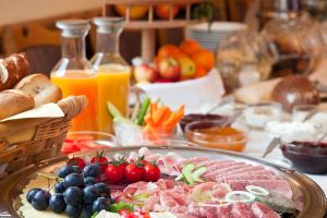 a table with a plate of meat and fruits and vegetables at Hotel bei Liebe's in Erlenbach am Main