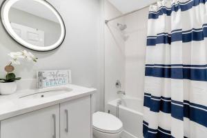 a white bathroom with a blue and white shower curtain at Everglade Kiss 3b 2b BBQ, hot tub in Port Charlotte +47 photos