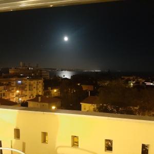 - une vue sur une ville la nuit avec une pleine lune dans l'établissement Top Sea View Lisboa - Oeiras, à Paço de Arcos