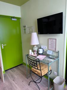 a room with a glass table with a lamp and a green door at Hôtel Restaurant Le Parc in Arc-en-Barrois