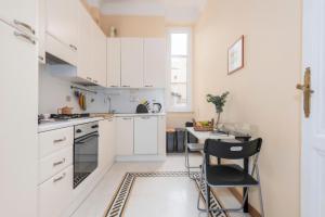 uma cozinha com armários brancos e uma mesa e cadeiras em TRASTEVERE APARTMENT - ZEN REAL ESTATE SRL em Roma