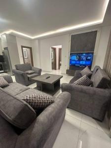 a living room with couches and a flat screen tv at cozy home near all services (21) in Rujm ash Sharāʼirah