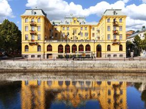 ein großes gelbes Gebäude neben einem Wasserkörper in der Unterkunft Elite Grand Hotel Gävle in Gävle