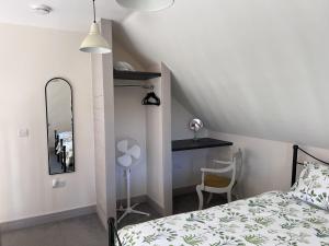 1 dormitorio con cama, escritorio y espejo en Poachers Hut - Captivating 1-bed Cottage Shorwell, en Shorwell