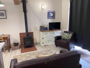 a living room with a couch and a stove at Poachers Hut - Captivating 1-bed Cottage Shorwell in Shorwell