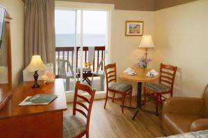 a living room with a table and a room with a view of the ocean at Hotel Motel Belle Plage in Matane