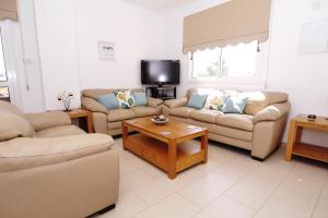 a living room with two couches and a tv at Maouris Villa in Protaras