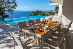 a dining table and chairs on a patio with a pool at Luxury Villa La Mirada in Omiš