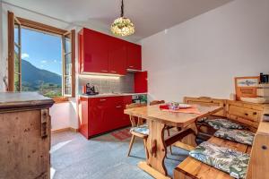 a kitchen with red cabinets and a wooden table at In val Bregaglia mille possibilità di benessere in Castasegna