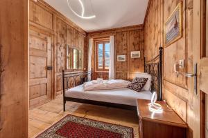 a bedroom with a bed in a room with wooden walls at In val Bregaglia mille possibilità di benessere in Castasegna