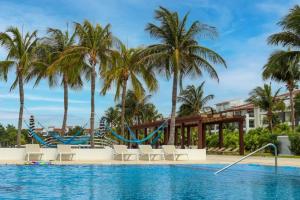 a swimming pool with chairs and palm trees at MAREAZUL Beachfront Apartment 2BR Private Pool Casa Áncora in Playa del Carmen