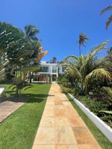 a walkway in front of a house with palm trees at BEACH VILLA Camurupim in Guajiru