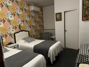 a hotel room with two beds and a floral wall at Hostal Pirineos in Barbastro