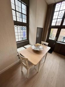 una mesa y sillas en una habitación con ventanas en Cozy Studio S2, City Centre Dordrecht, en Dordrecht