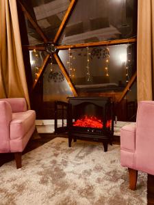 a living room with a fireplace and two chairs at Phalesia Glamping Otel in Sapanca