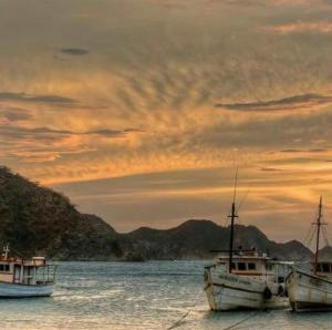 three boats sitting in the water at sunset at ANCON HOUSE in Taganga