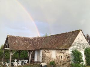 CoulongéPetit Moulin Renaissance的石屋上方的彩虹,配有桌椅