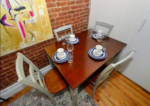a wooden table with chairs and plates and cups on it at Spacious 2 Bed 1 Bath In Mid West in New York