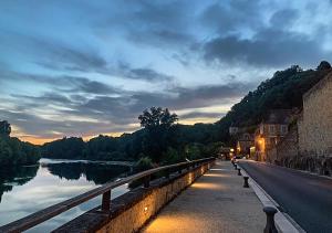 a bridge over a river next to a body of water at Au coeur de Beynac, une maison de caractère avec jardin terrasse in Beynac-et-Cazenac