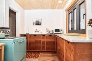 een keuken met houten kasten en een blauwe koelkast bij Casa de la Muxer - 940s Adobe - Hot Tub - Cowboy Pool in Twentynine Palms