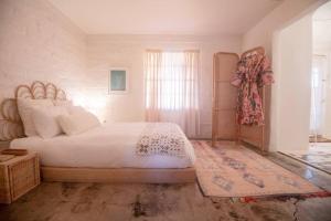 een slaapkamer met een groot bed en een raam bij Casa de la Muxer - 940s Adobe - Hot Tub - Cowboy Pool in Twentynine Palms