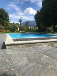 a blue swimming pool with a stone walkway at Ferienwohnung mit Garten und Pool in Ascona in Ascona