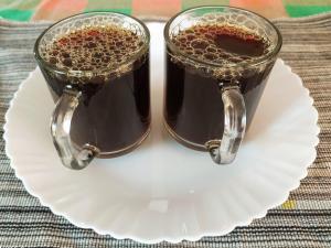 two glasses of coffee sitting on a plate at kannur west beach homestay in Kannur