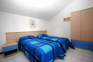 two beds in a bedroom with blue comforters at Holiday Village in Lignano Sabbiadoro